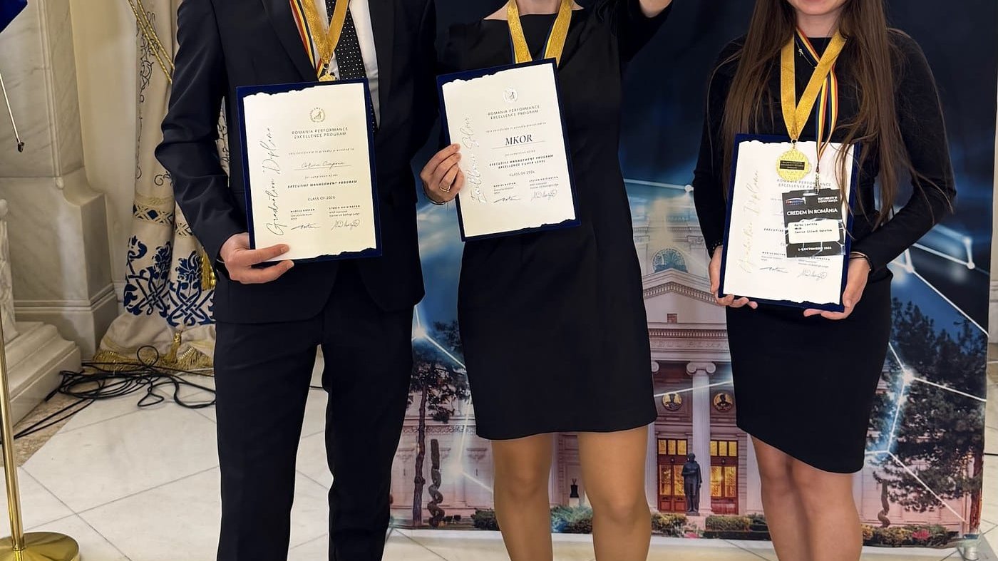 Trei membri ai echipei MKOR zâmbesc cu certificatele RPEP în mână, iar colega din mijloc ridică trofeul Excellence Silver, în fața panoului RePatriot Summit.